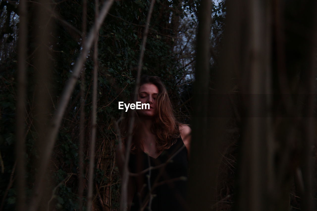 Young woman amidst plants in forest