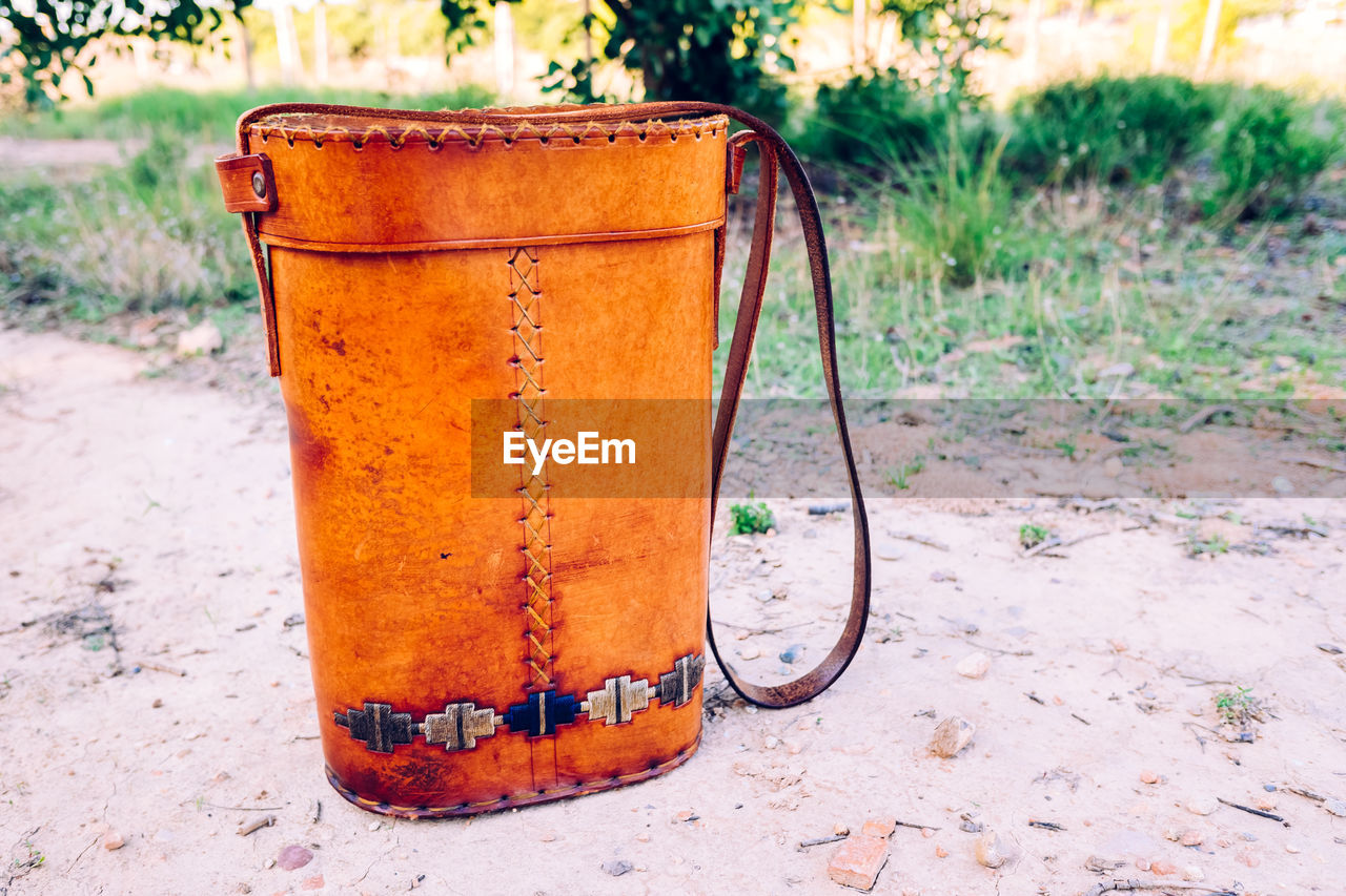 CLOSE-UP OF RUSTY METAL ON FIELD BY LAND