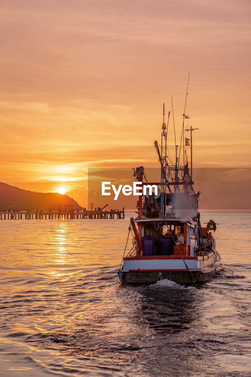 BOAT SAILING IN SEA AGAINST ORANGE SKY