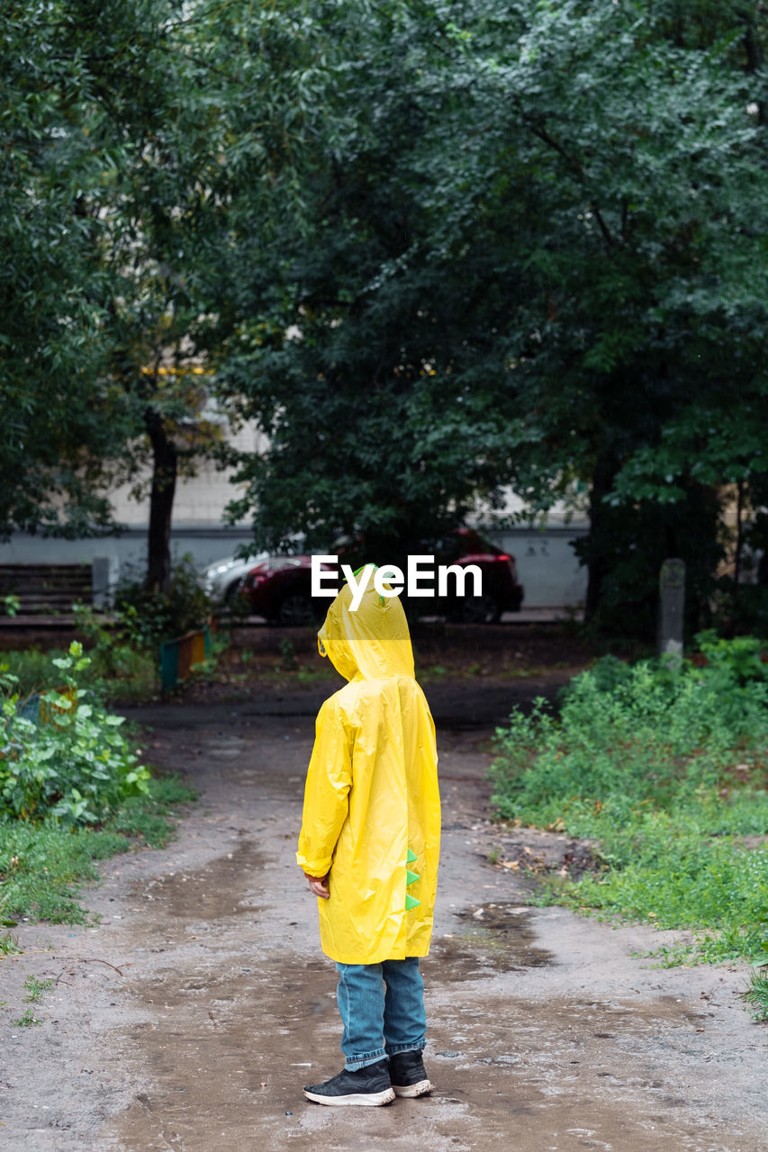 A lonely boy in a yellow raincoat got lost in the park