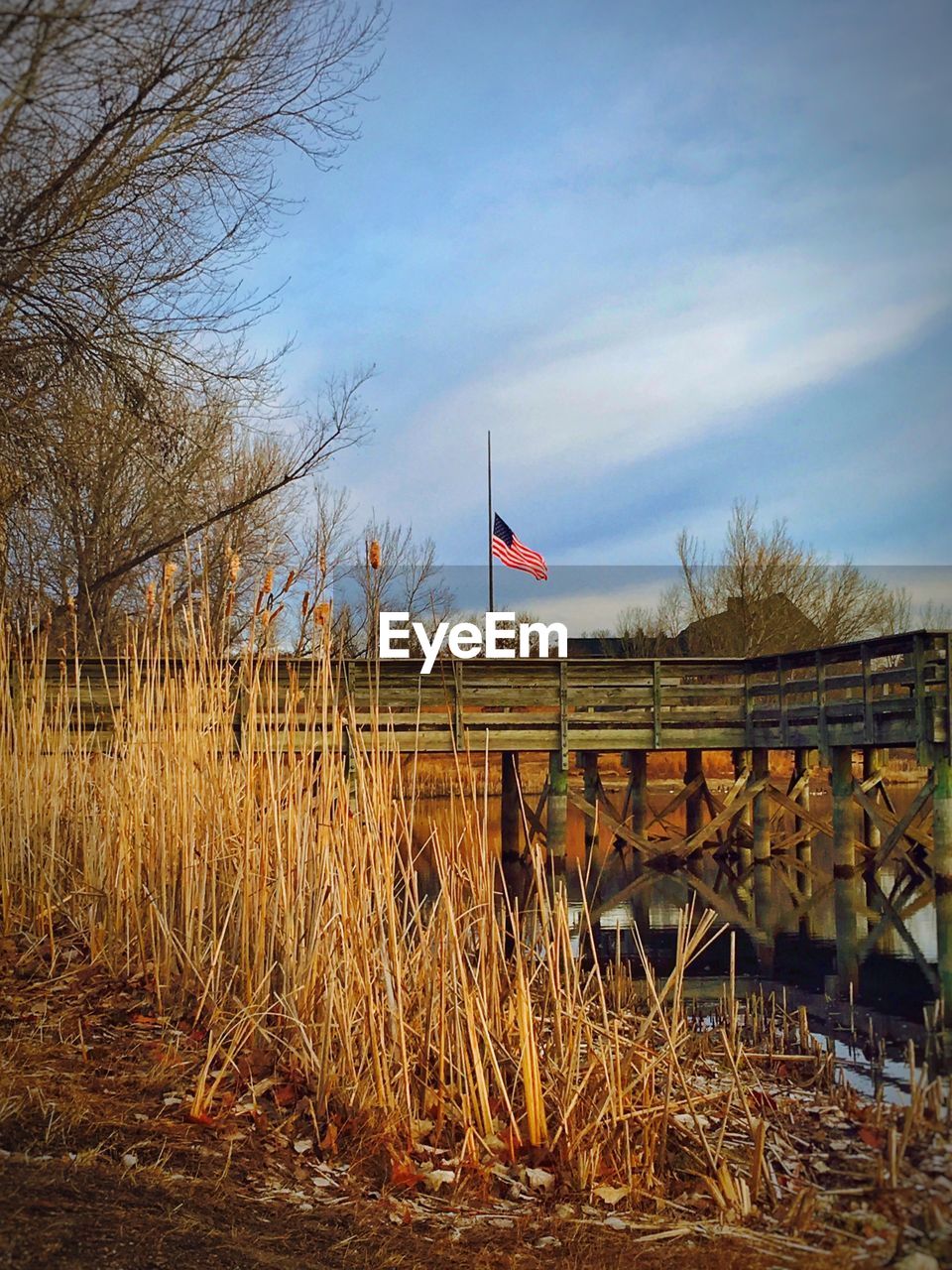 Pier on lake by field against sky