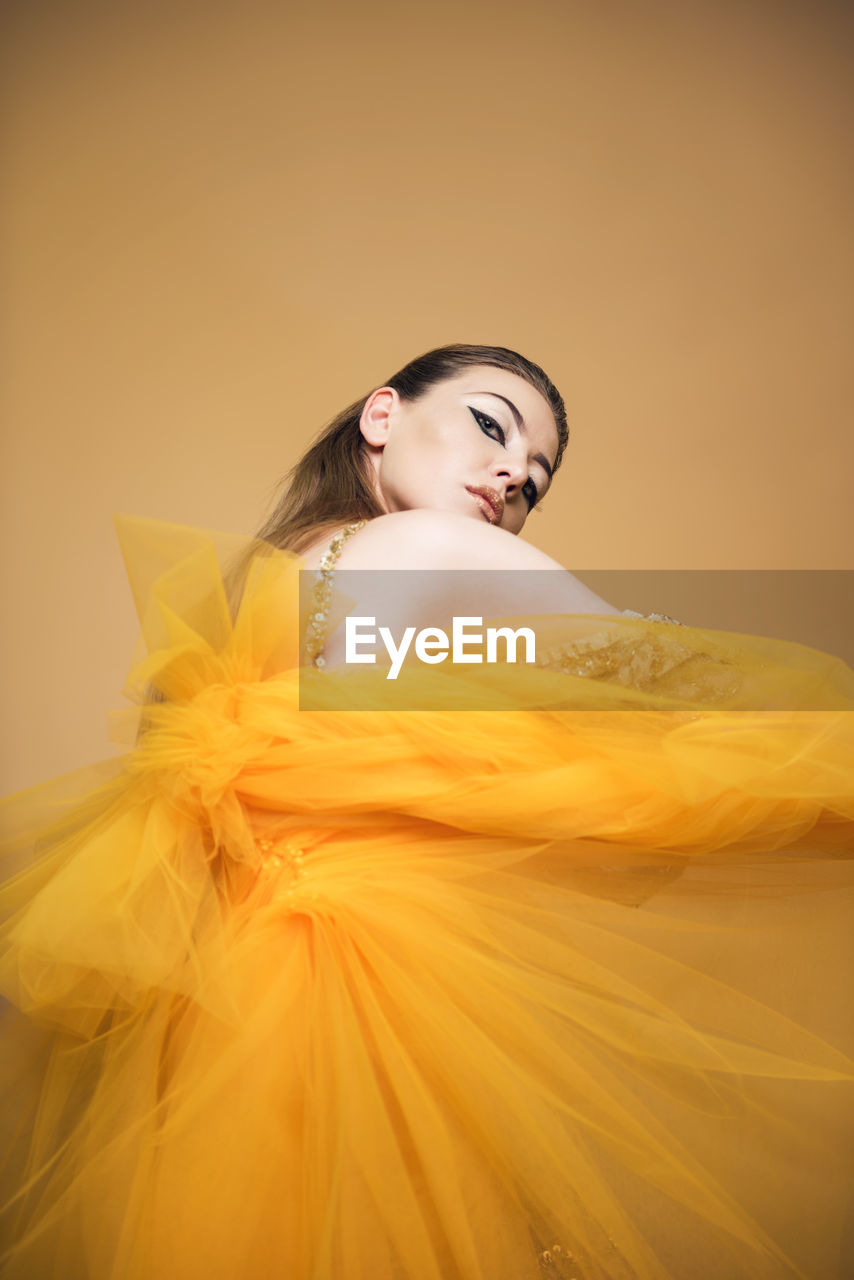 CLOSE-UP OF YOUNG WOMAN AGAINST YELLOW COLORED BACKGROUND