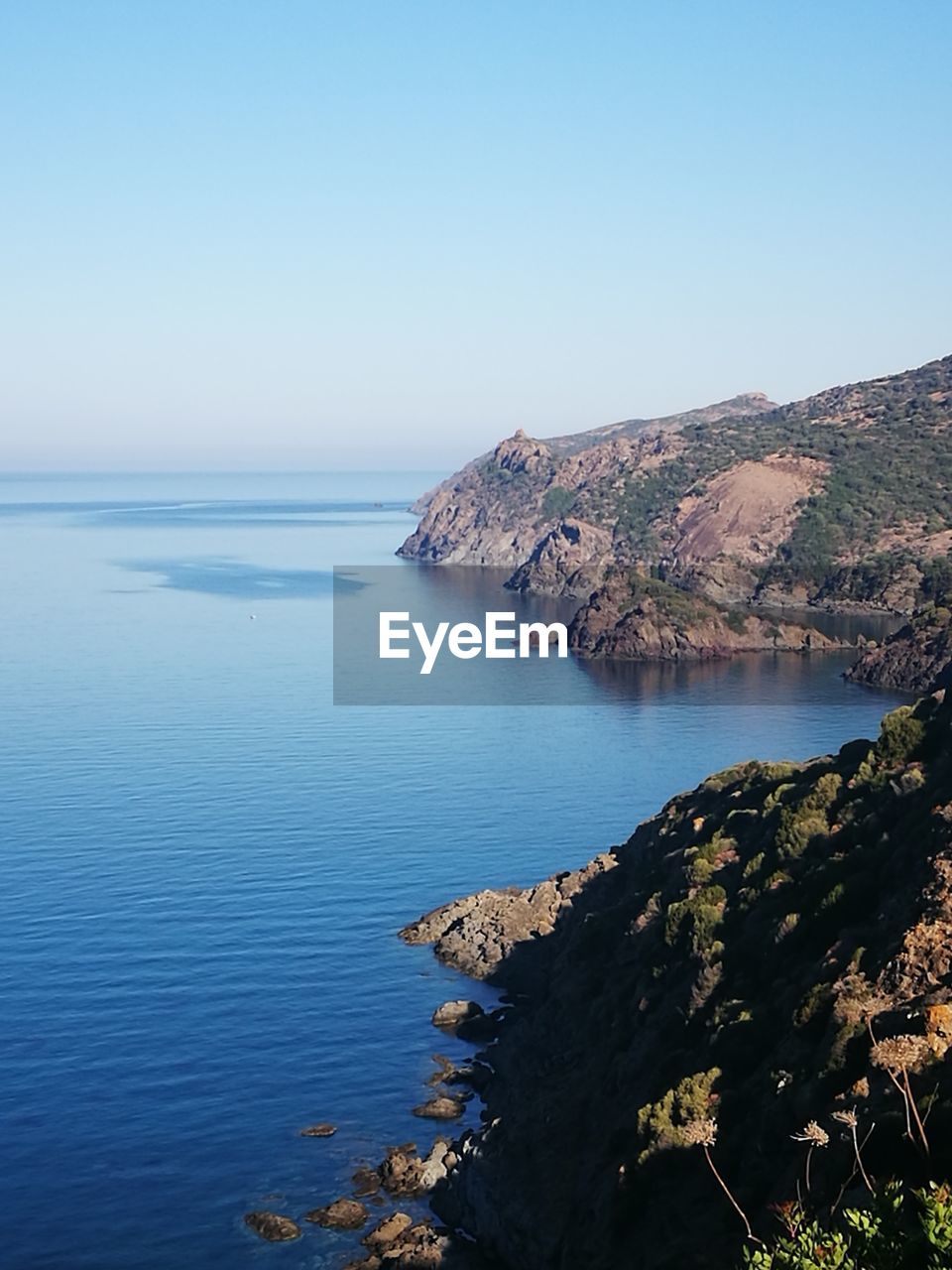 Scenic view of sea and mountains against clear sky