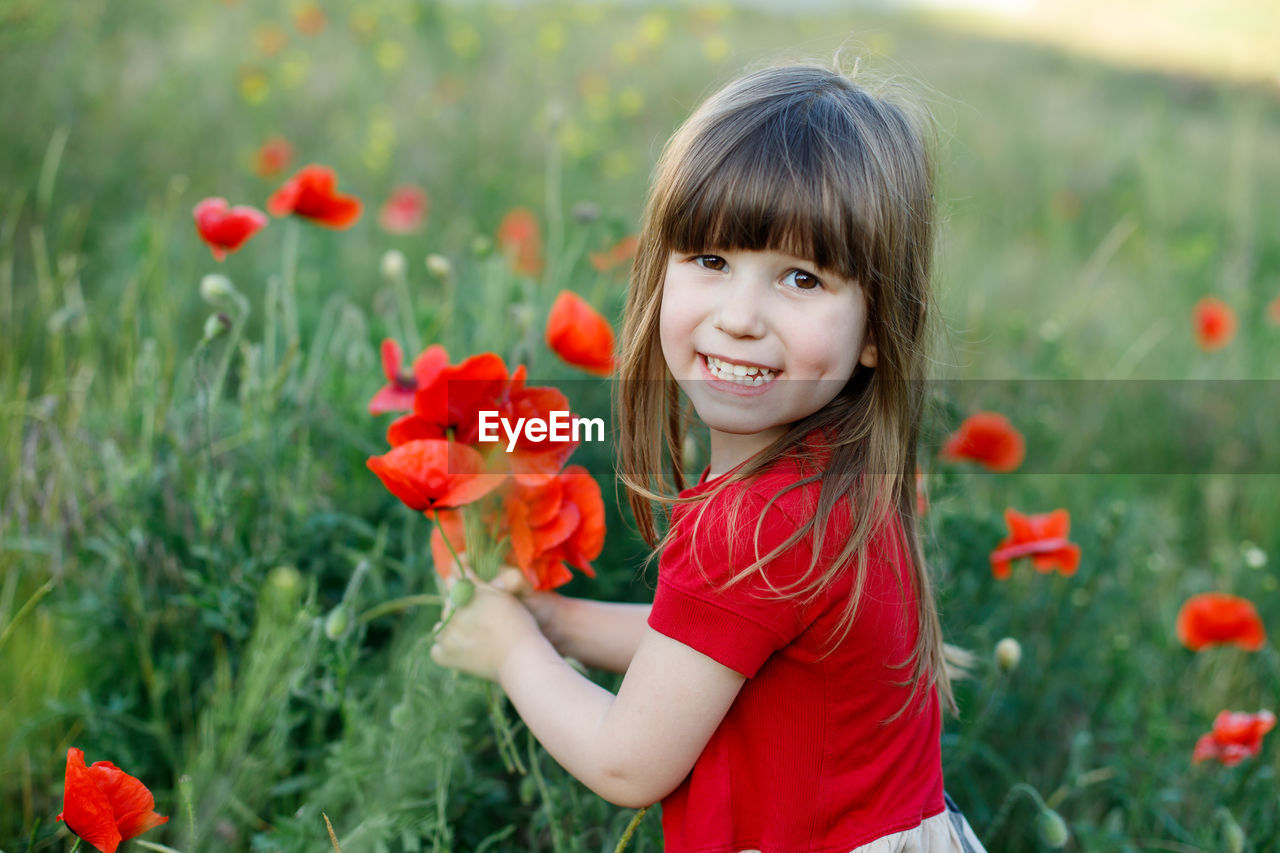 PORTRAIT OF A SMILING GIRL WITH RED FLOWER
