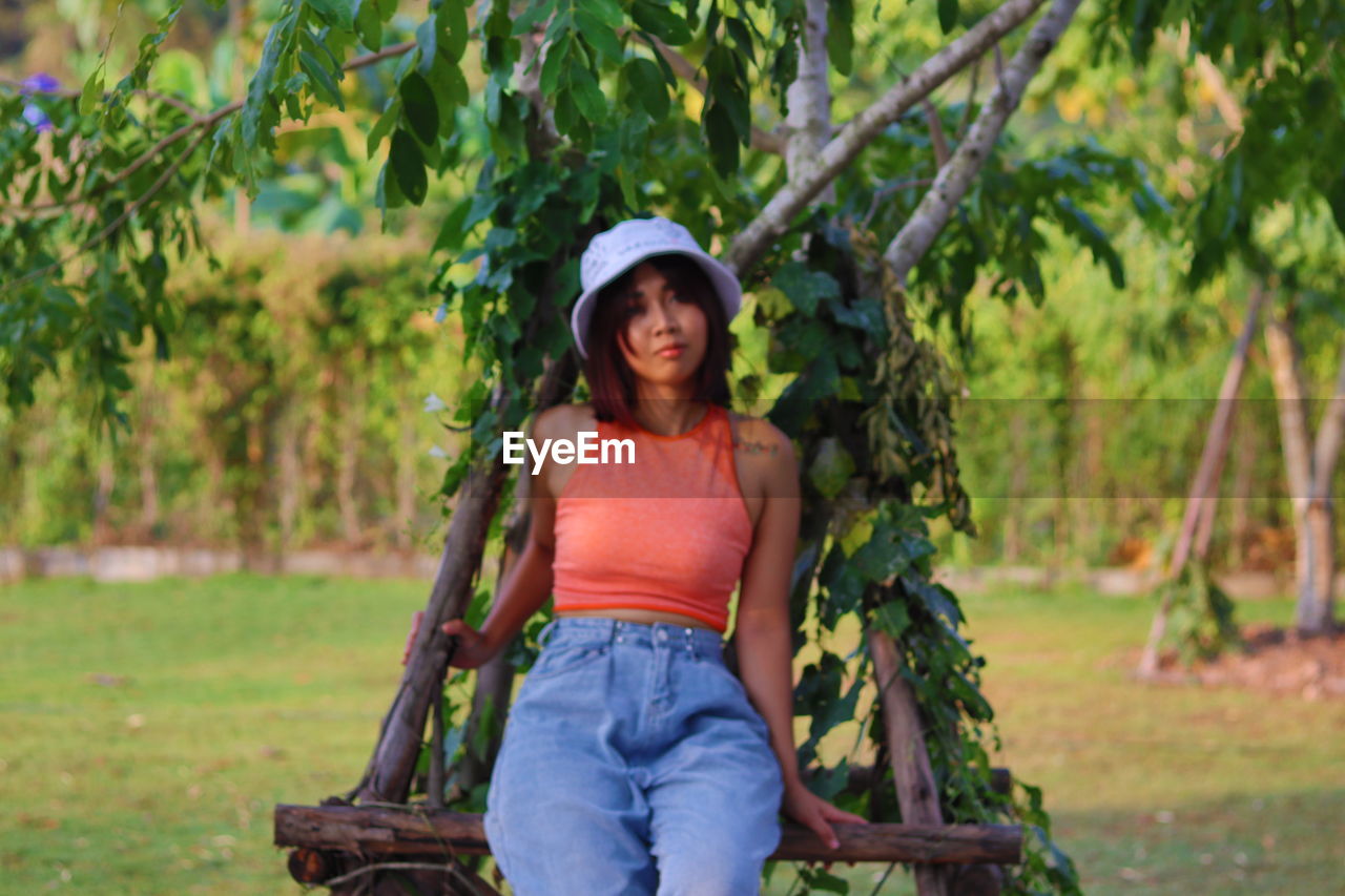 PORTRAIT OF HAPPY GIRL SITTING ON TREE