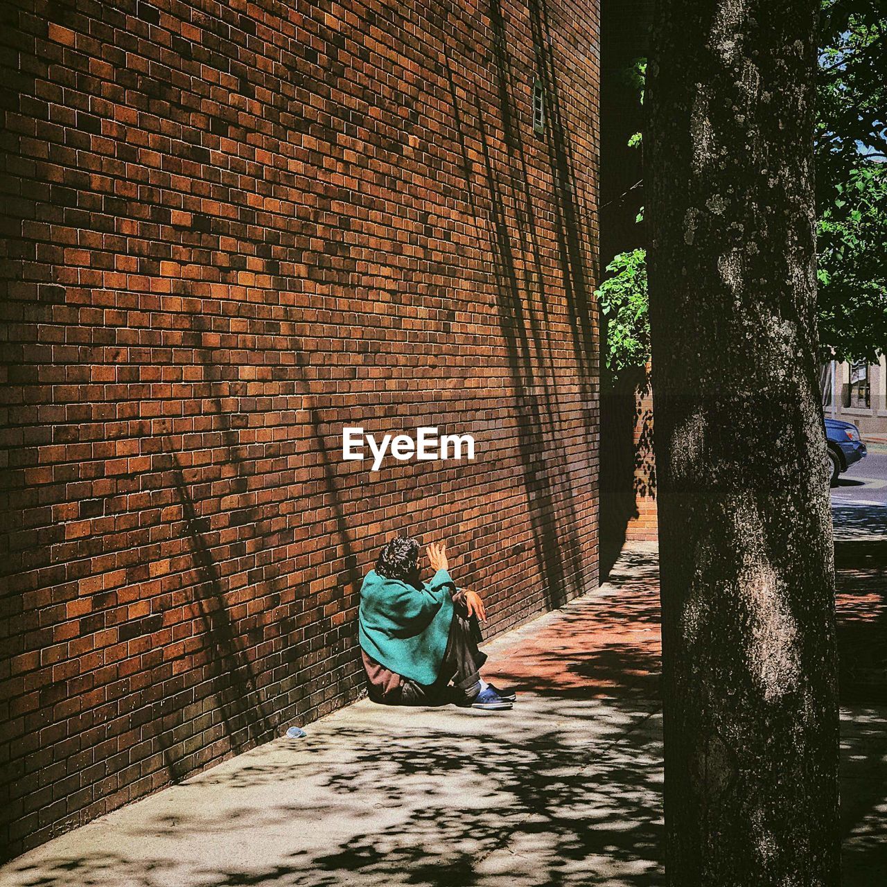 Man sitting against wall in city