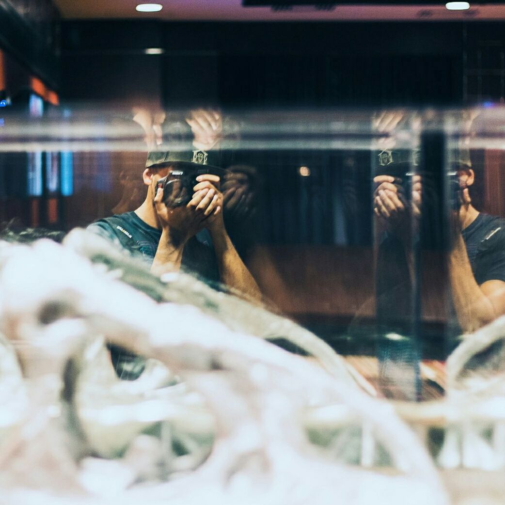 Reflection of man photographing indoors