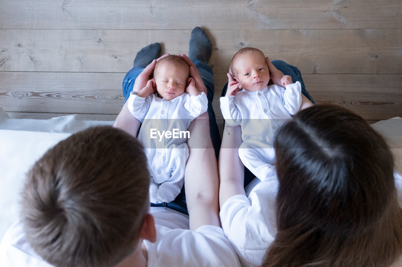 Newborn identical twins on the bed, on a parents hands. life style, emotions of kids. infant babies 