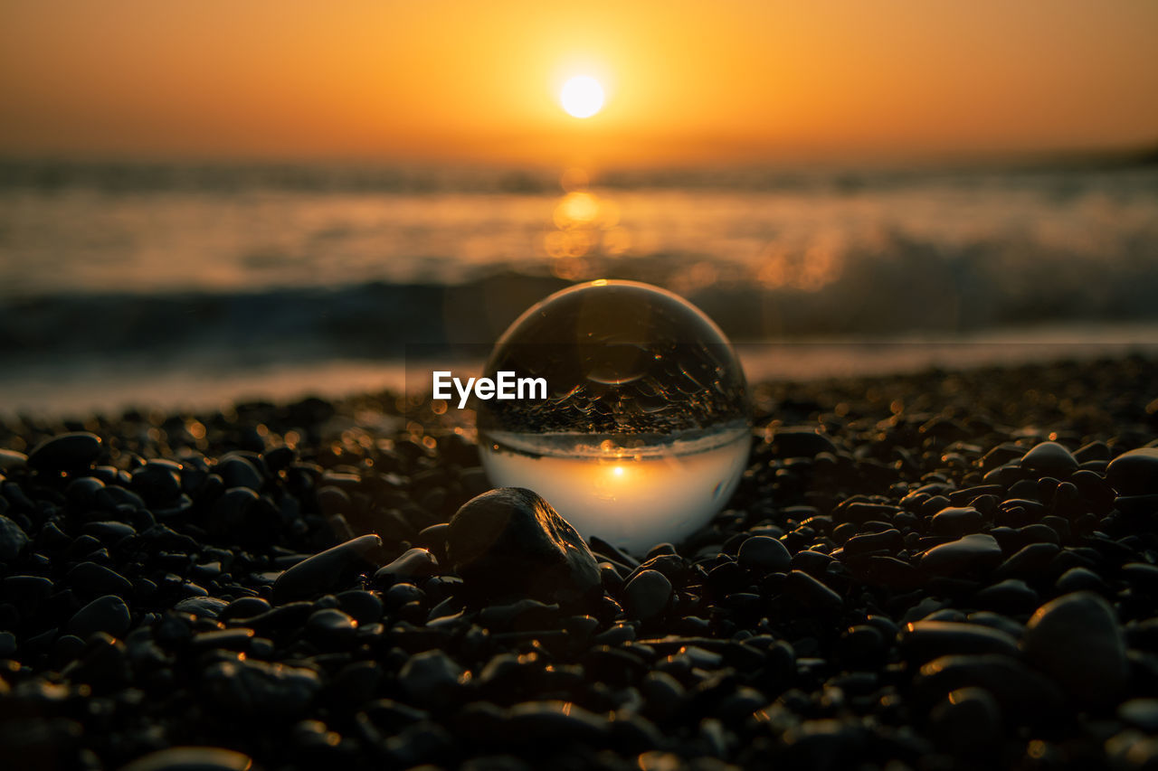 Close-up of crystal ball on beach during sunset