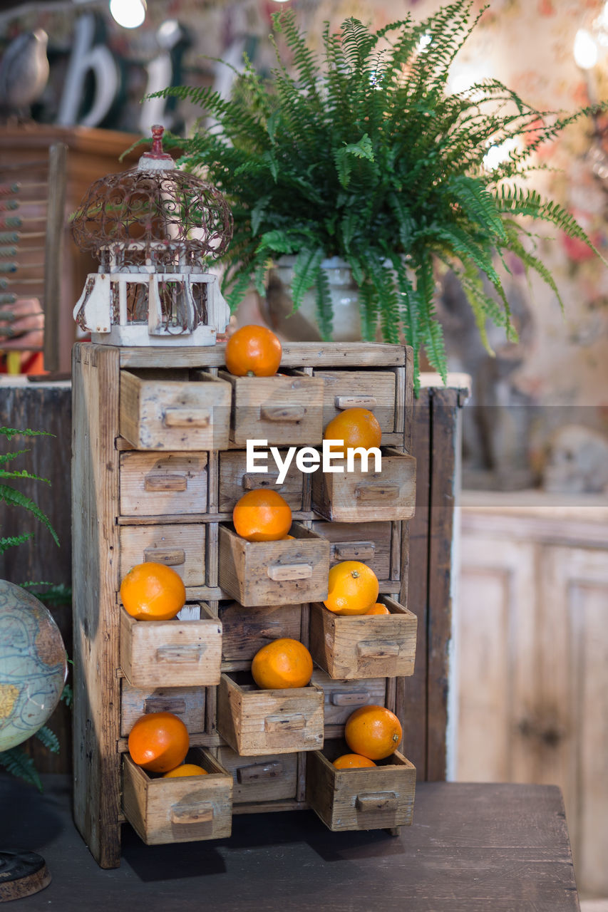 Small wooden chest of drawers with open drawers and orange fruits resting on top.