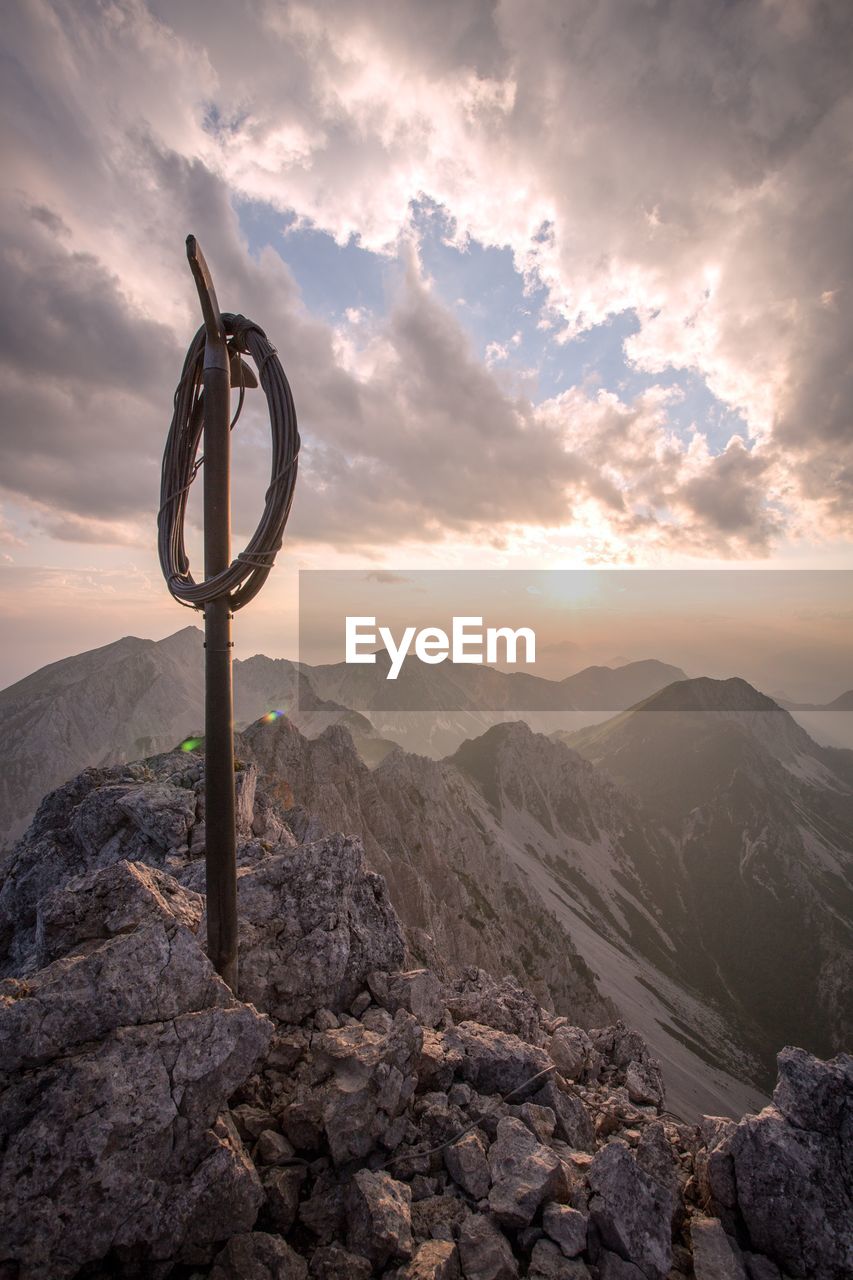 CROSS ON ROCK AGAINST SKY DURING SUNSET