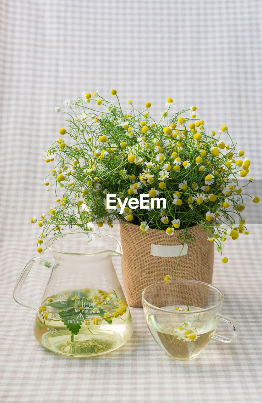 Close-up of flowers with jar and cup