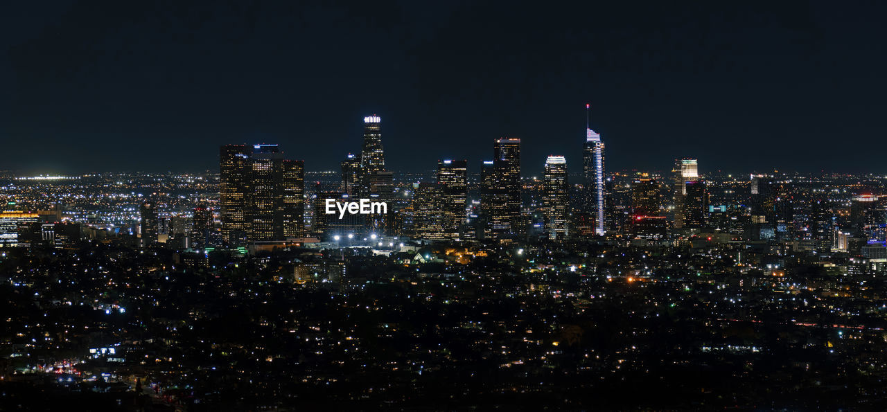 Illuminated cityscape against sky at night