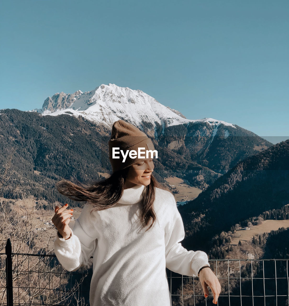 Young woman standing against snowcapped mountain and sky