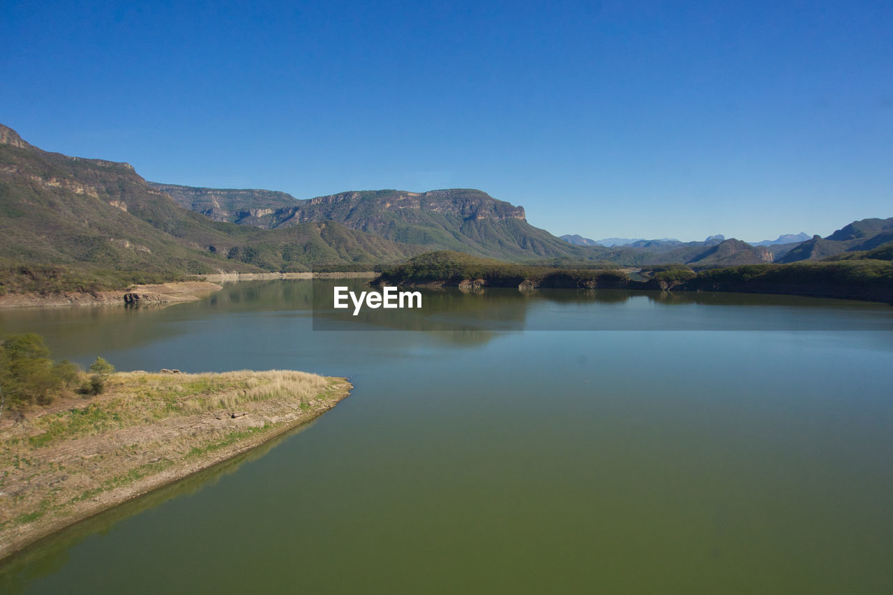 Scenic high view of lake and mountains against clear blue sky