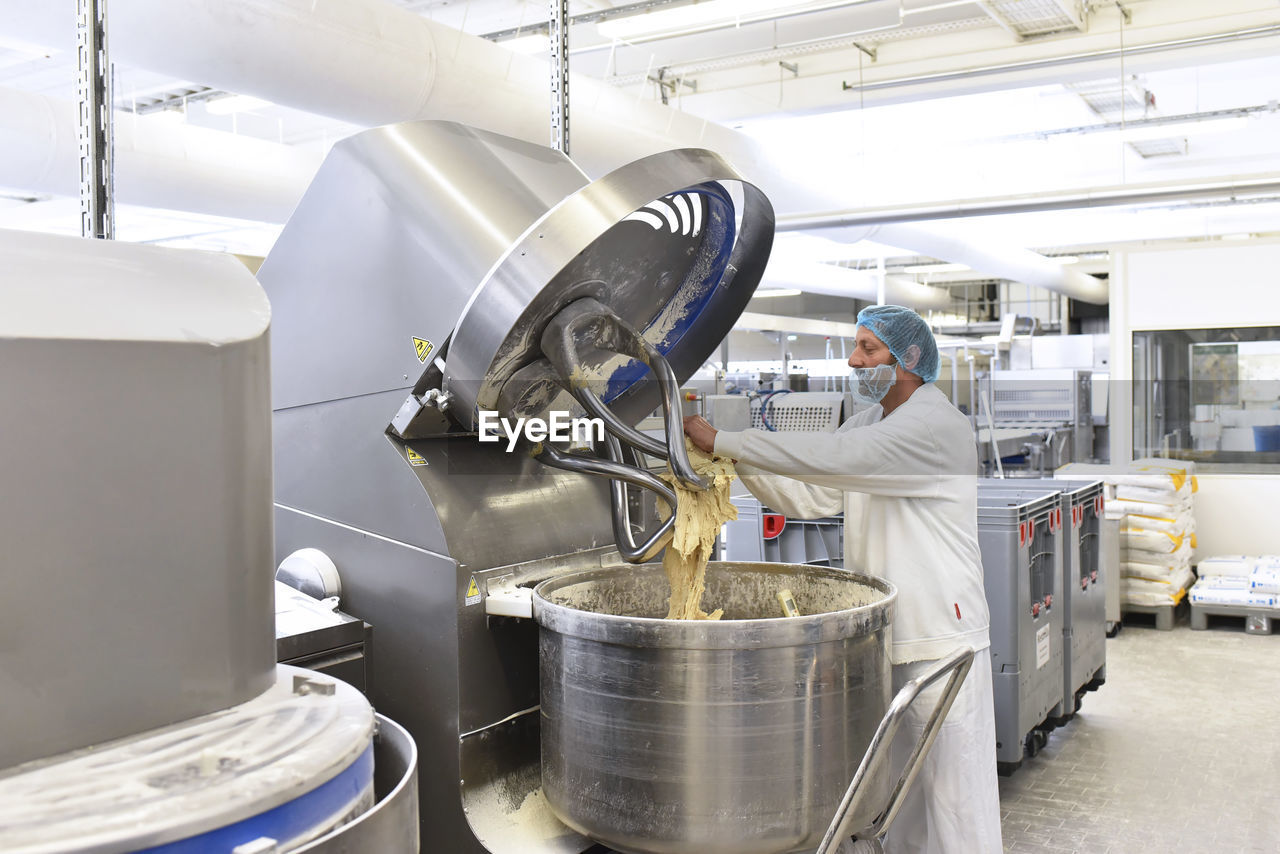 Worker operating dough kneading machine in an industrial bakery