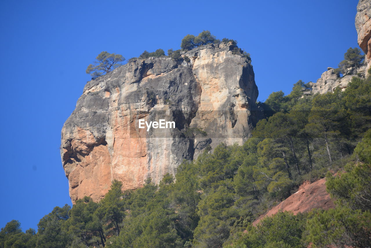 rock, sky, nature, scenics - nature, tree, mountain, plant, beauty in nature, land, travel destinations, rock formation, environment, blue, travel, clear sky, landscape, non-urban scene, no people, cliff, outdoors, park, tranquility, mountain range, tourism, pine tree, tranquil scene, national park, adventure, sunny, coniferous tree, forest, day, low angle view, pinaceae, geology, idyllic, wilderness, mountain peak, steep, terrain, physical geography, leisure activity, extreme terrain, sunlight