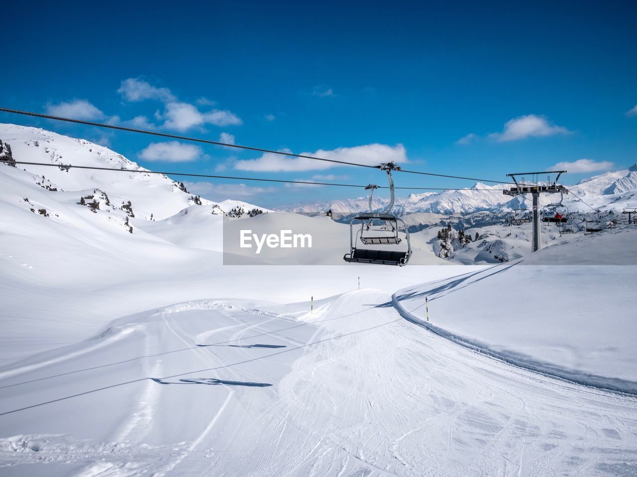 Ski lift over snowcapped mountains against sky