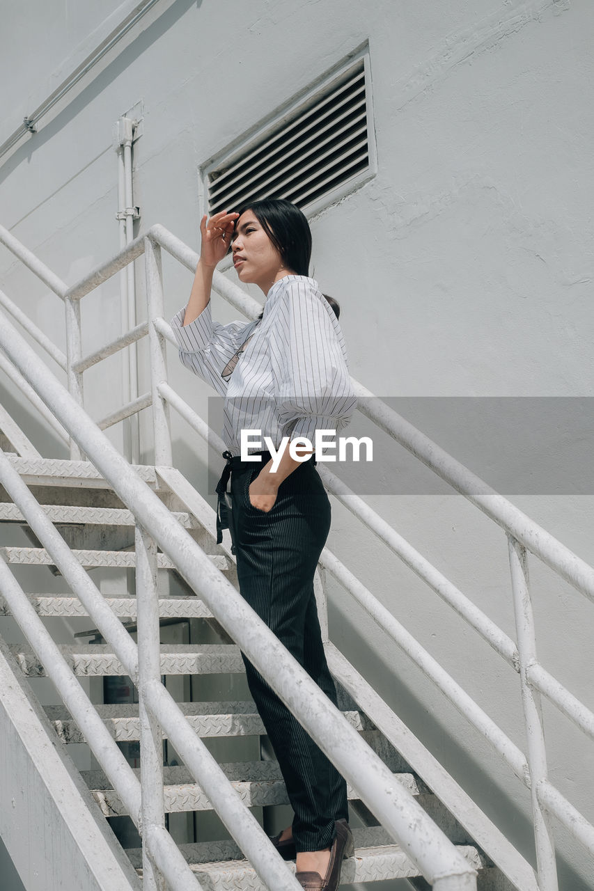 Full length of young woman standing on staircase