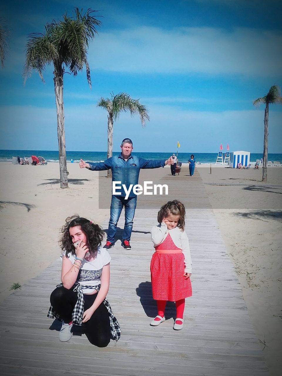 FULL LENGTH PORTRAIT OF SIBLINGS STANDING ON BEACH AGAINST SKY