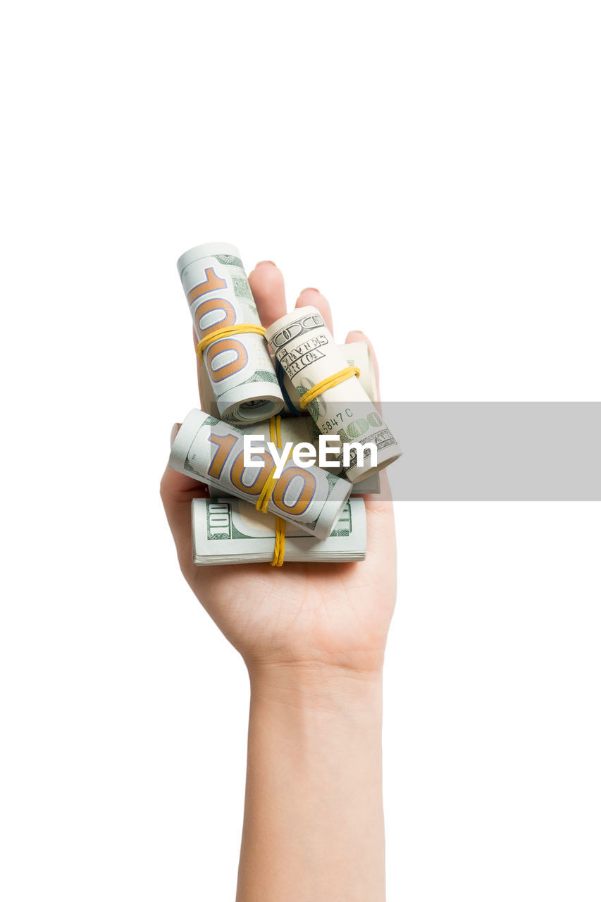 Close-up of hand holding paper currency against white background