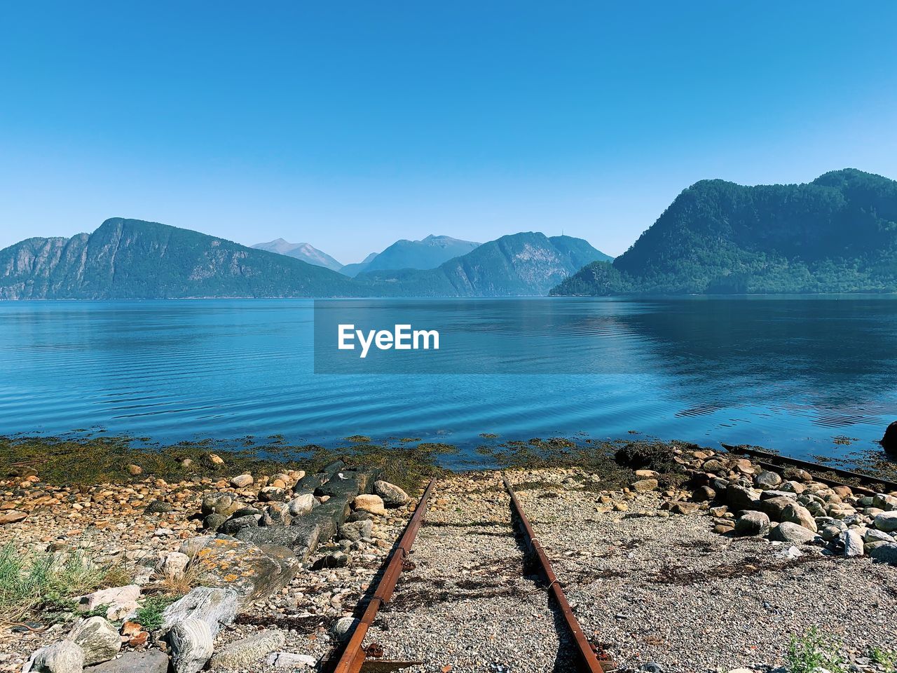 Scenic view of lake against clear blue sky