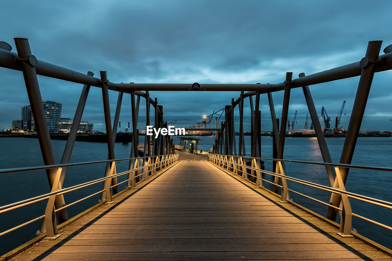 Bridge over sea against cloudy sky