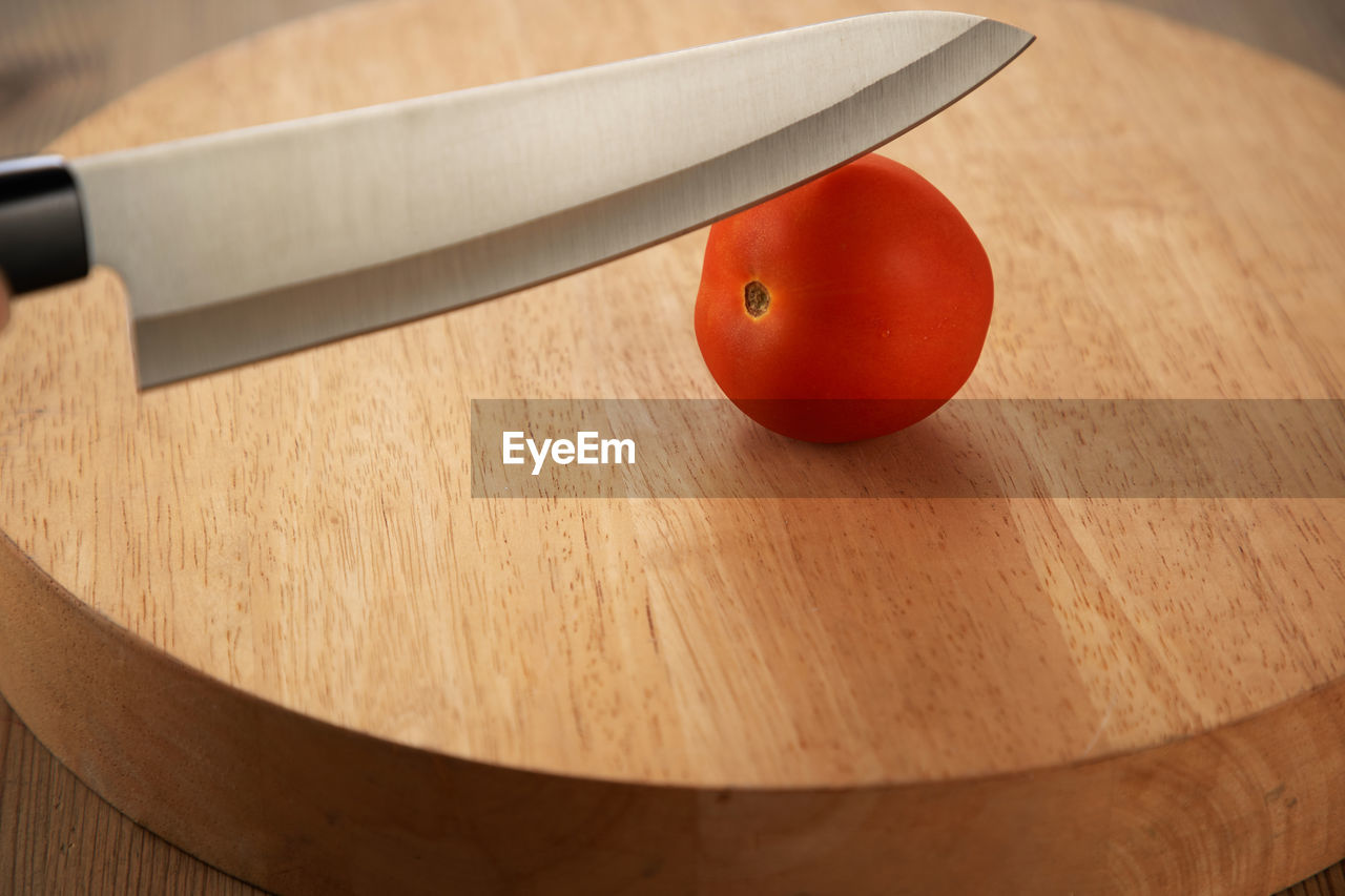 High angle view of kitchen knife and tomato on cutting board