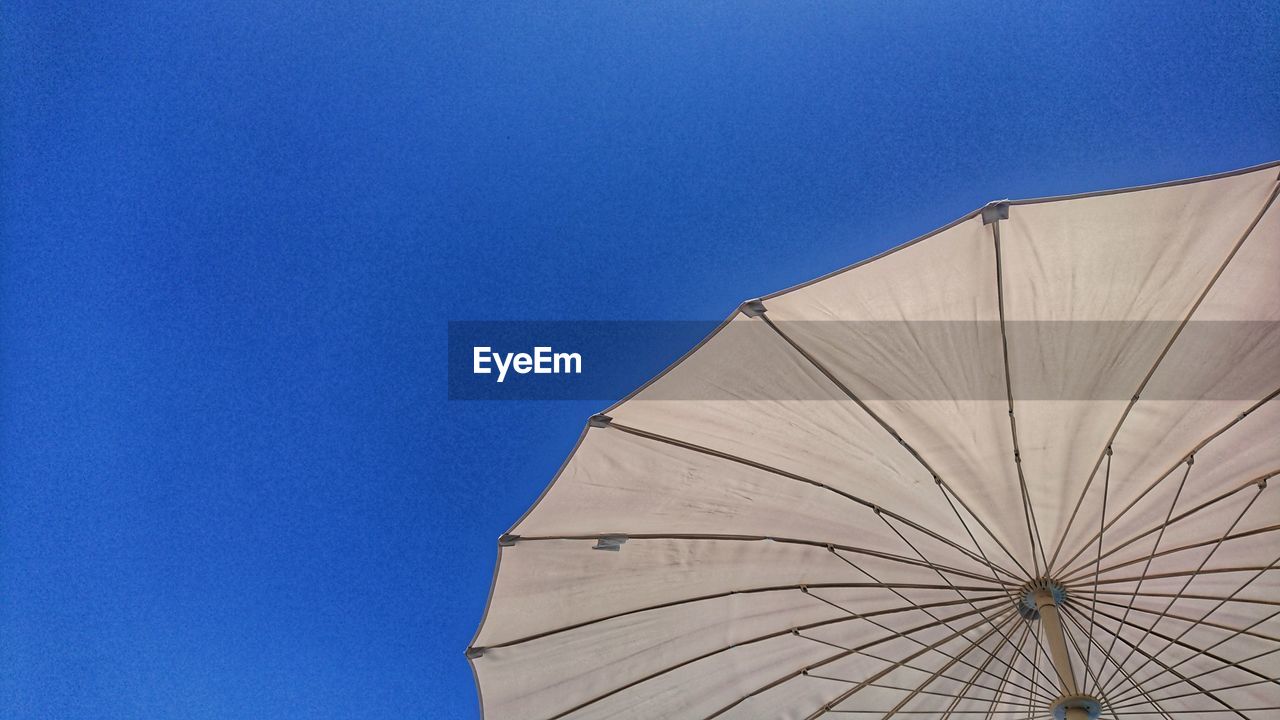 Low angle view of umbrella against clear blue sky