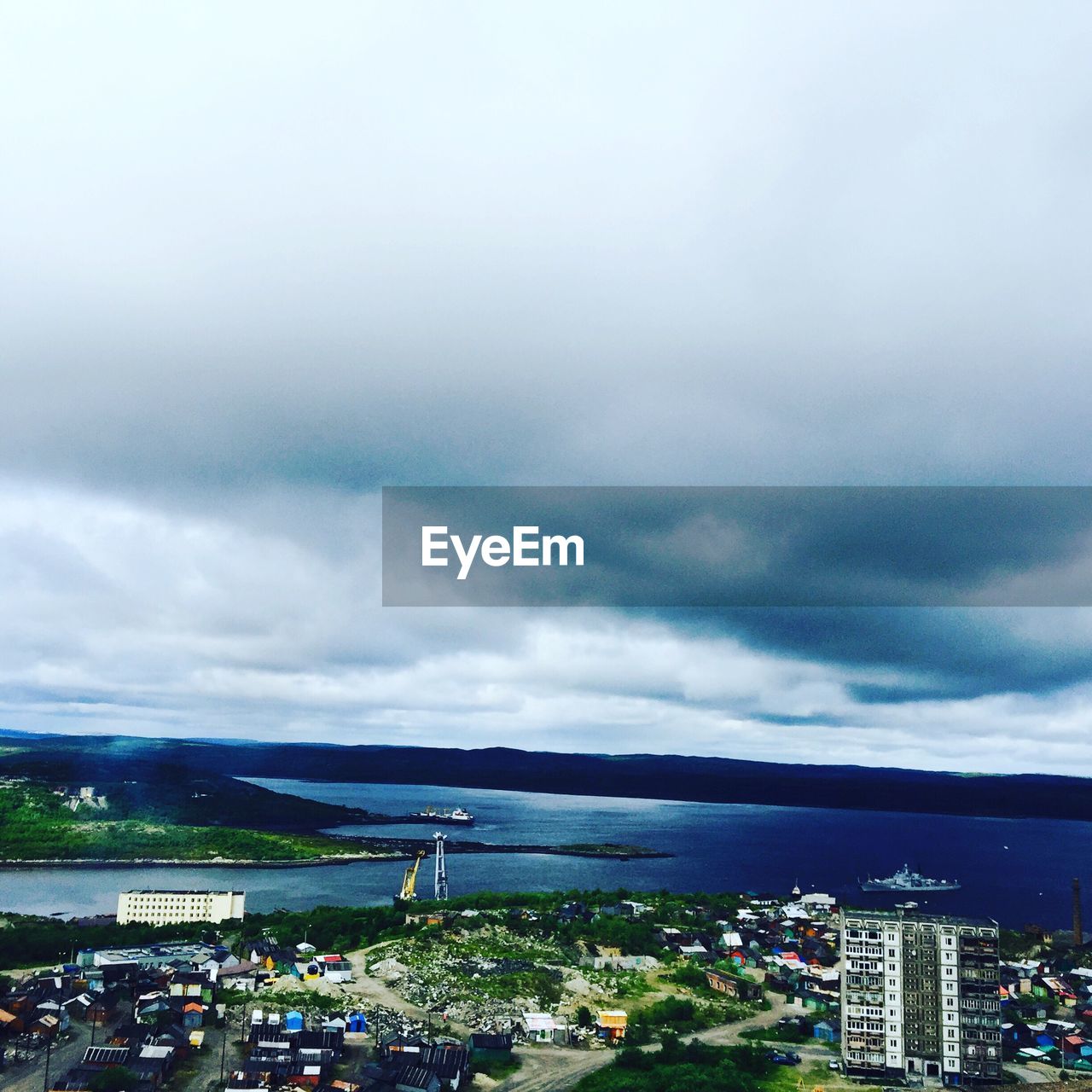 HIGH ANGLE VIEW OF CITYSCAPE AGAINST CLOUDY SKY