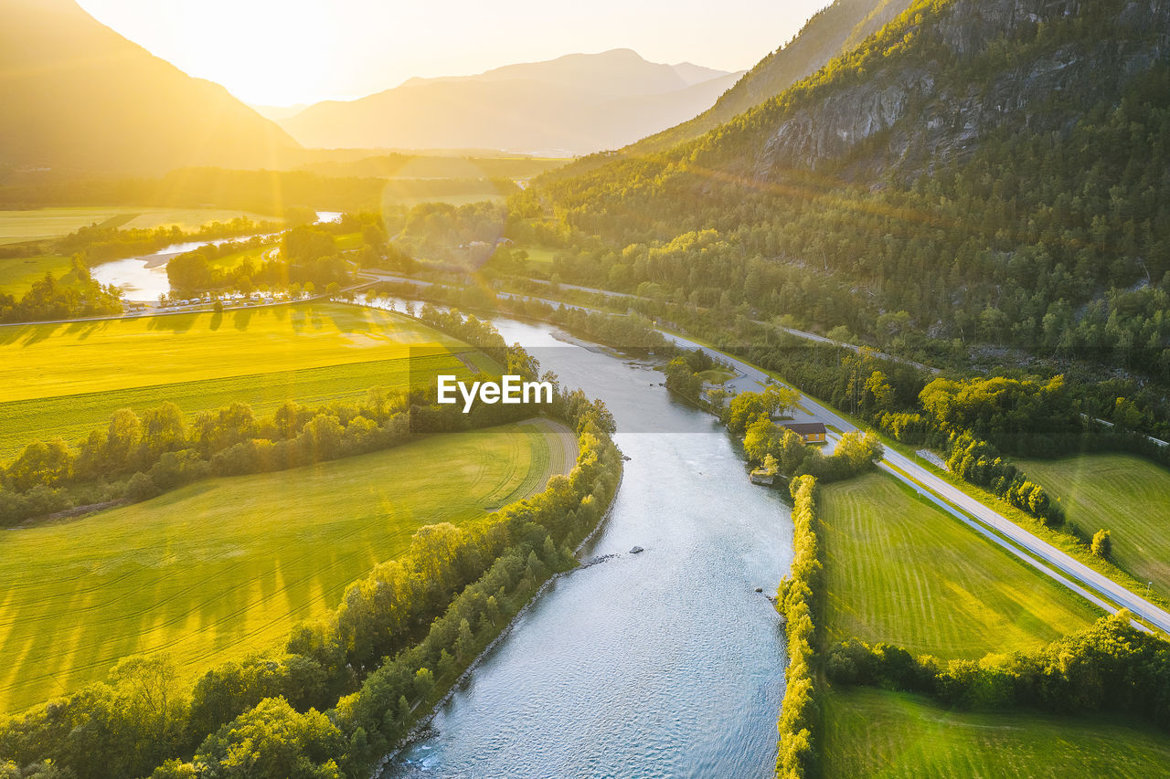 Scenic view of agricultural field by river against sky