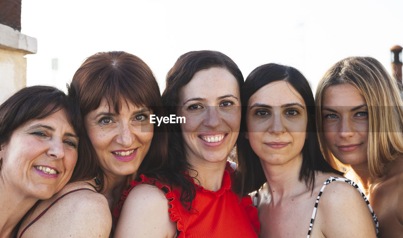 Close-up portrait of female friends against clear sky