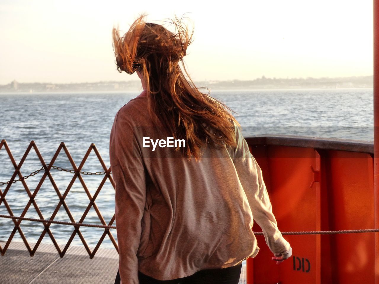 Rear view of woman standing on pier over sea