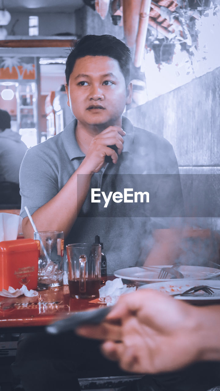 Portrait of young man sitting at restaurant