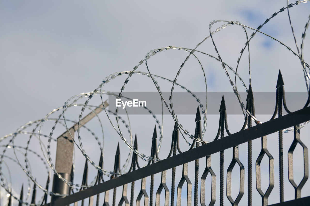 Barbed wire on fence, steel grating fence, metal fence wire. coiled razor wire with steel barbs