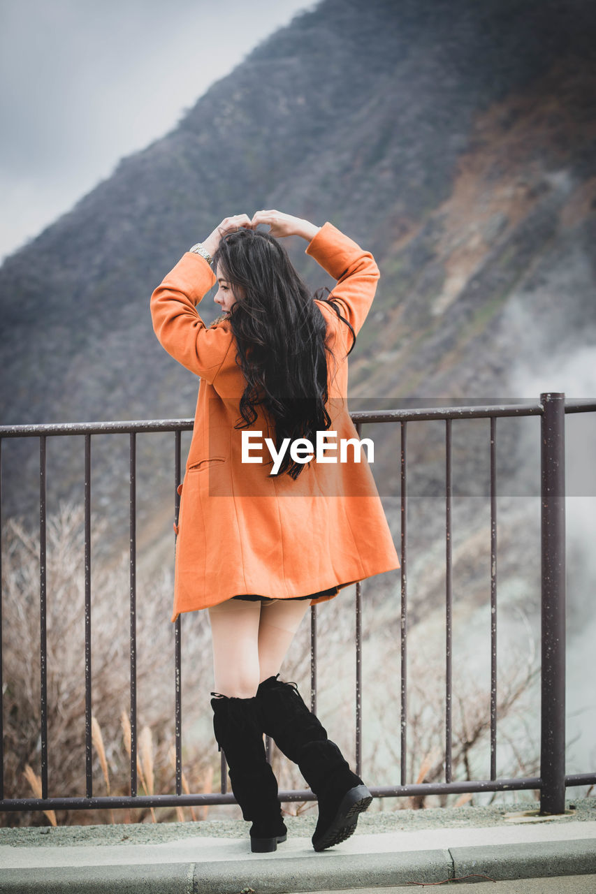 Rear view of woman standing on footpath by railing