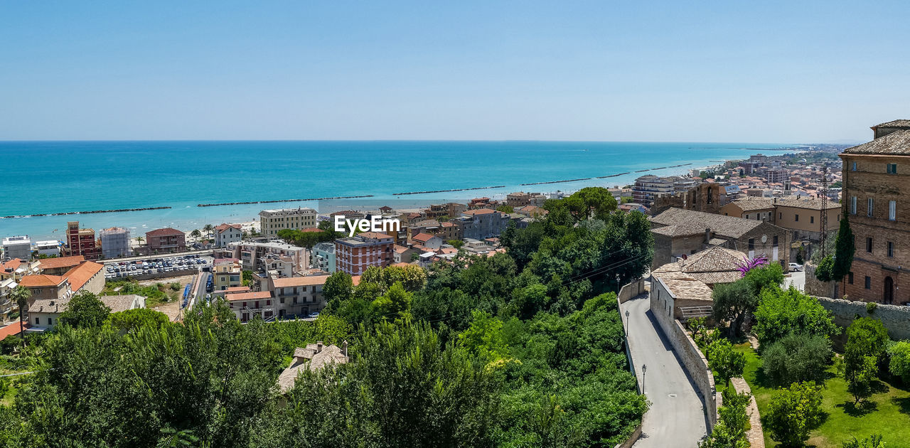 High angle view of townscape by sea against clear sky