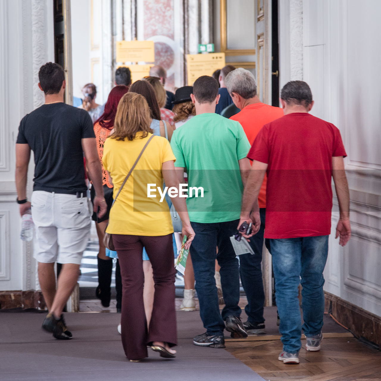 REAR VIEW OF PEOPLE WALKING IN FRONT OF AN ANIMAL