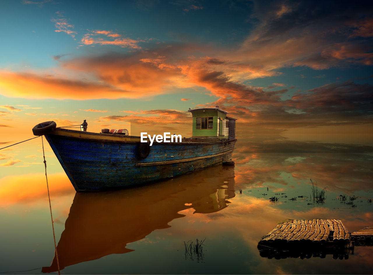 SHIP MOORED AT LAKE AGAINST SKY DURING SUNSET