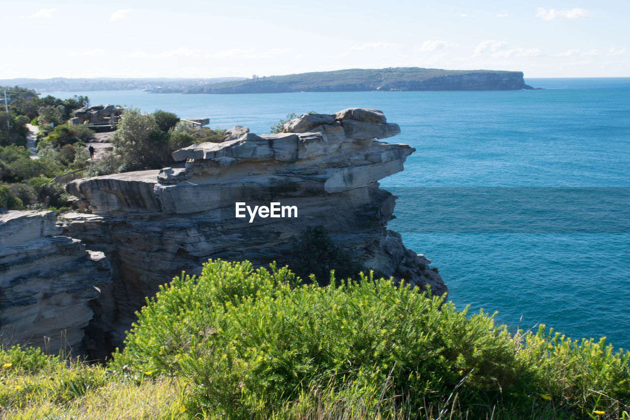 Scenic view of cliff by sea against sky