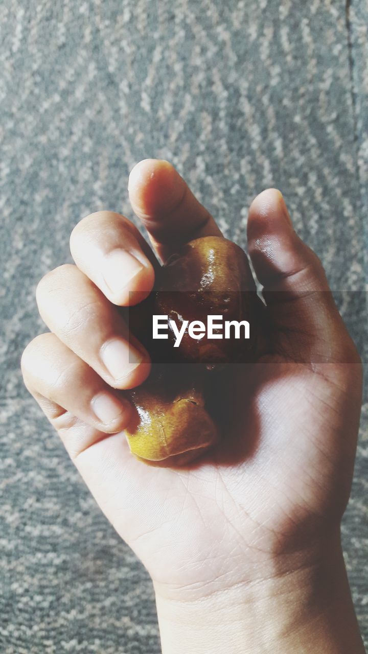 CLOSE-UP OF PERSON HAND HOLDING FRUIT