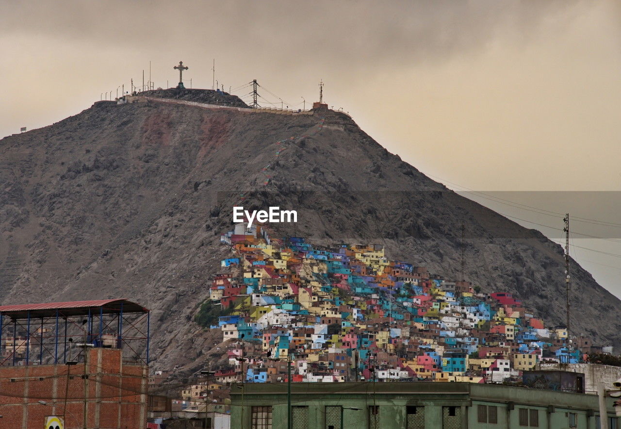 architecture, built structure, building exterior, mountain, sky, building, nature, travel destinations, flag, environment, cloud, multi colored, city, religion, outdoors, urban area, no people, travel, tradition, landscape, history, tourism, house, belief