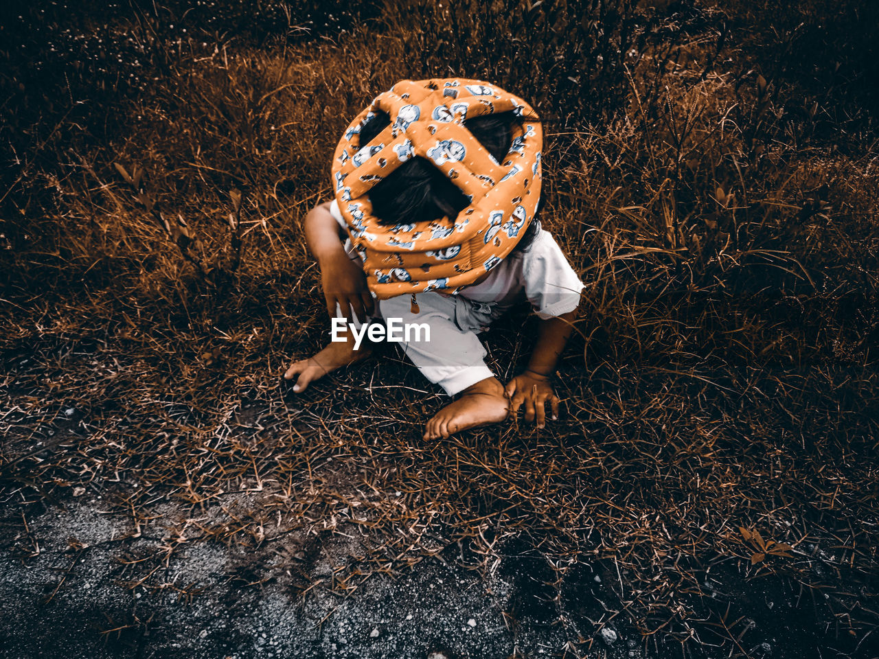 High angle view of baby girl wearing hat sitting on grassy land