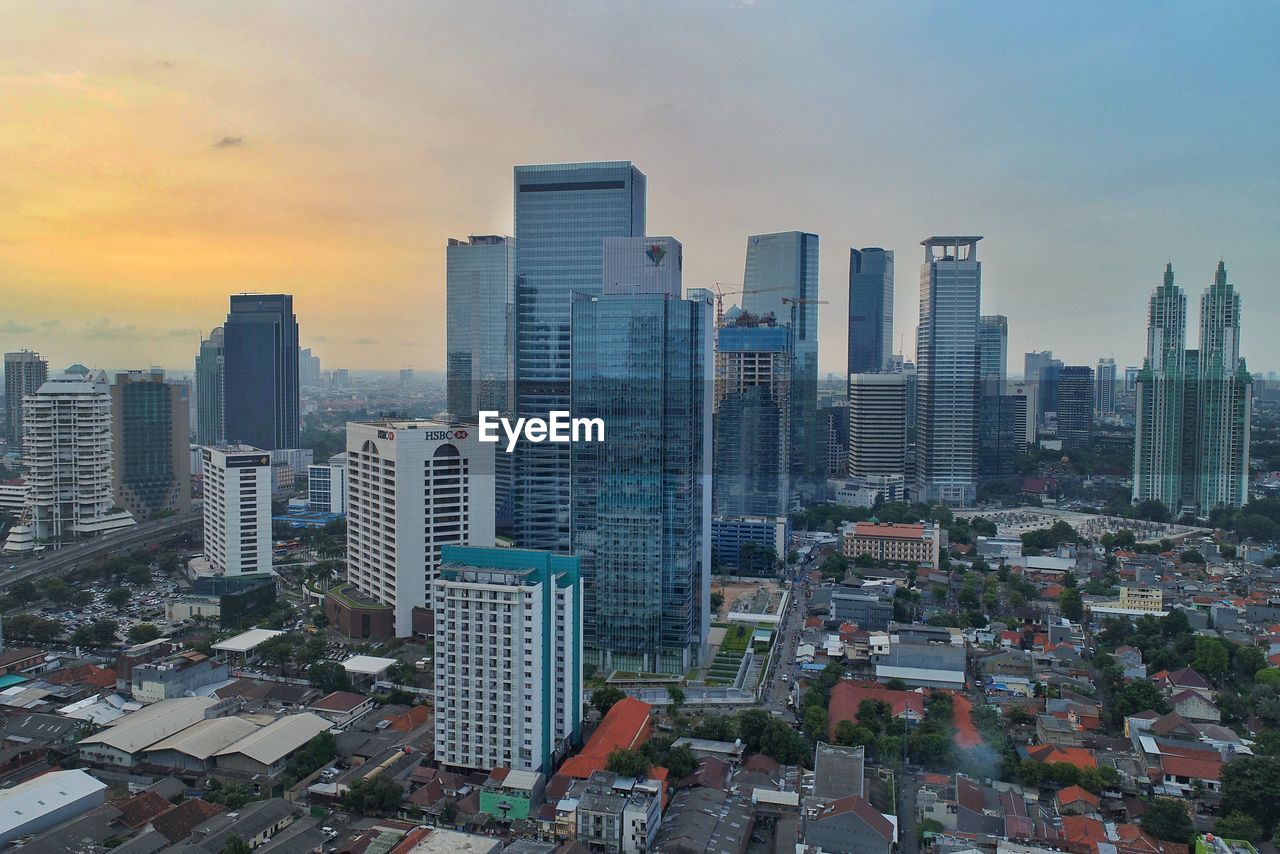 Aerial view of buildings in city against sky during sunset