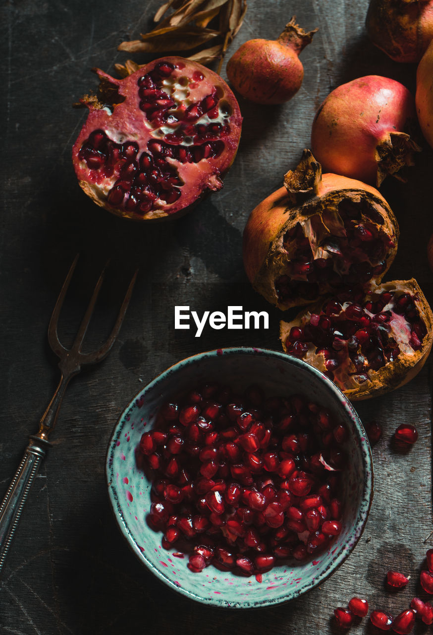 Top view of pile of colorful fresh pomegranates arranged on table with dried plants