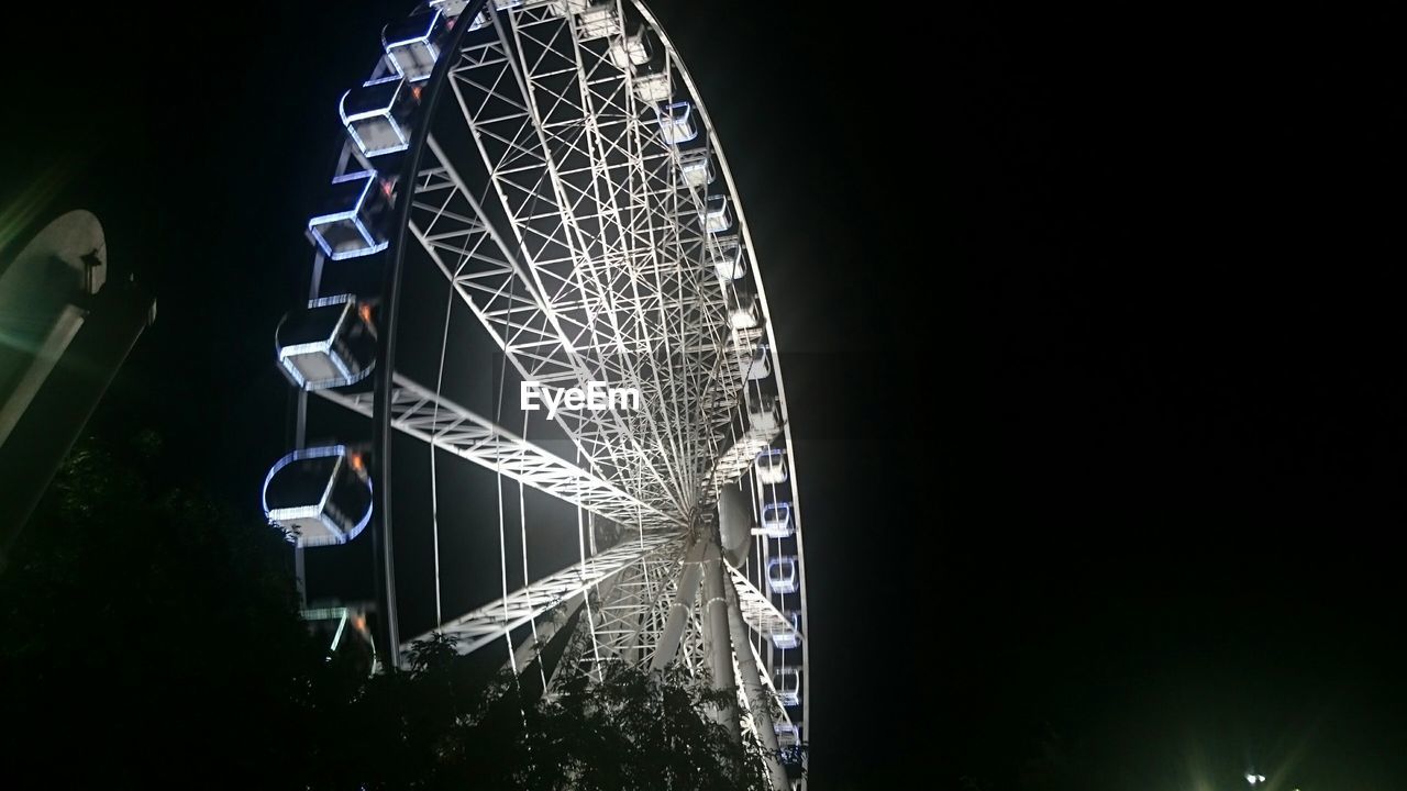 LOW ANGLE VIEW OF ILLUMINATED FERRIS WHEEL AT NIGHT