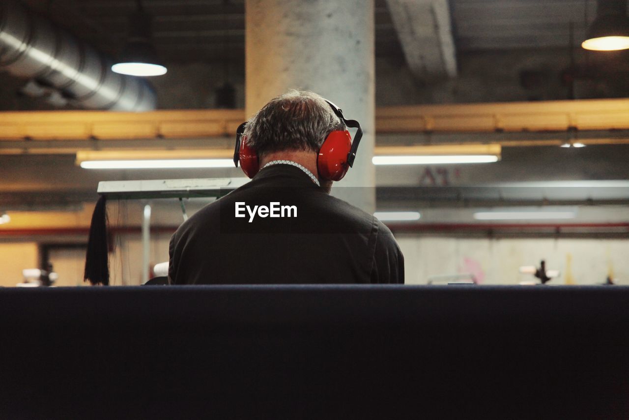 Rear view of man listening to music in textile factory