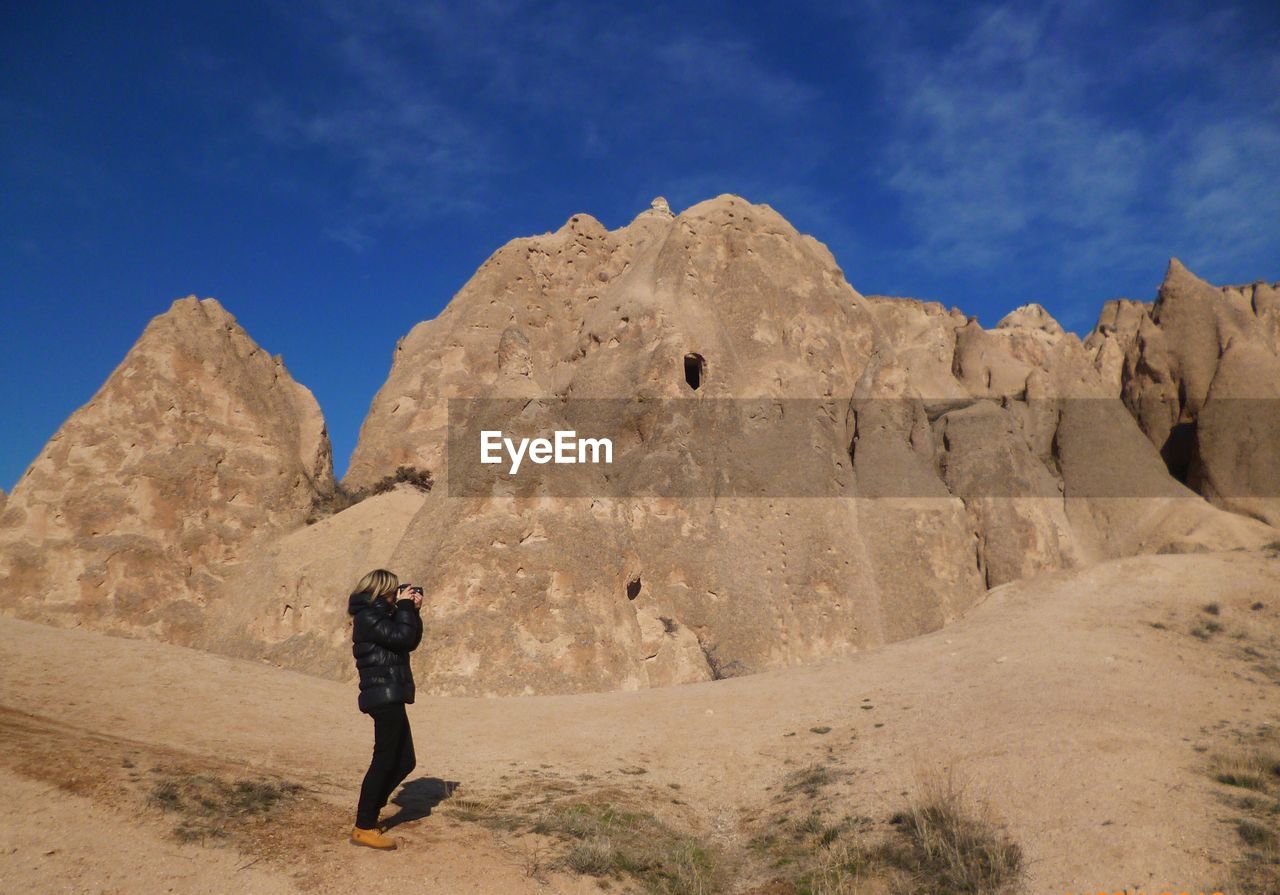 Woman photographing mountains against sky