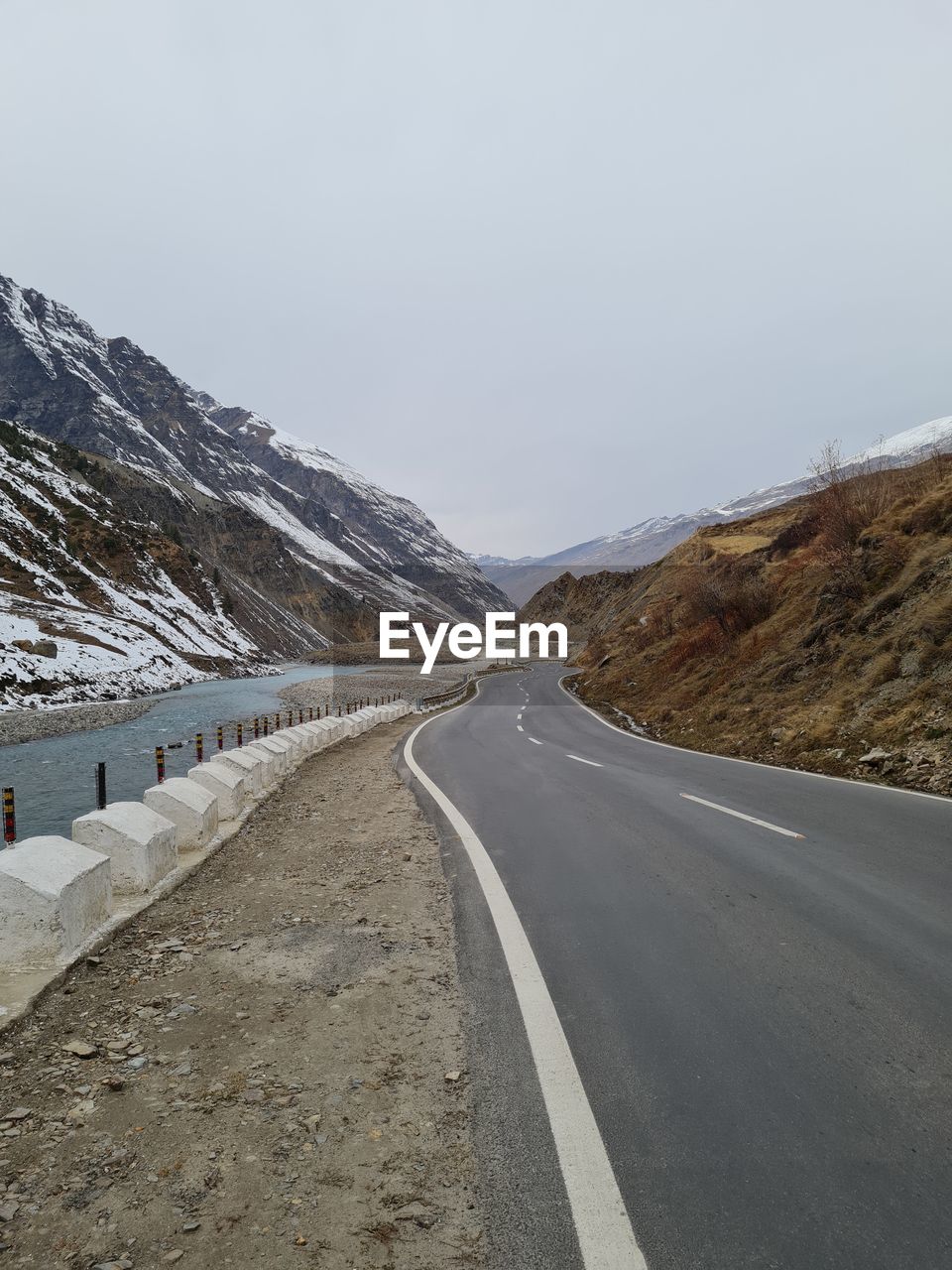 EMPTY ROAD ALONG SNOW COVERED MOUNTAIN