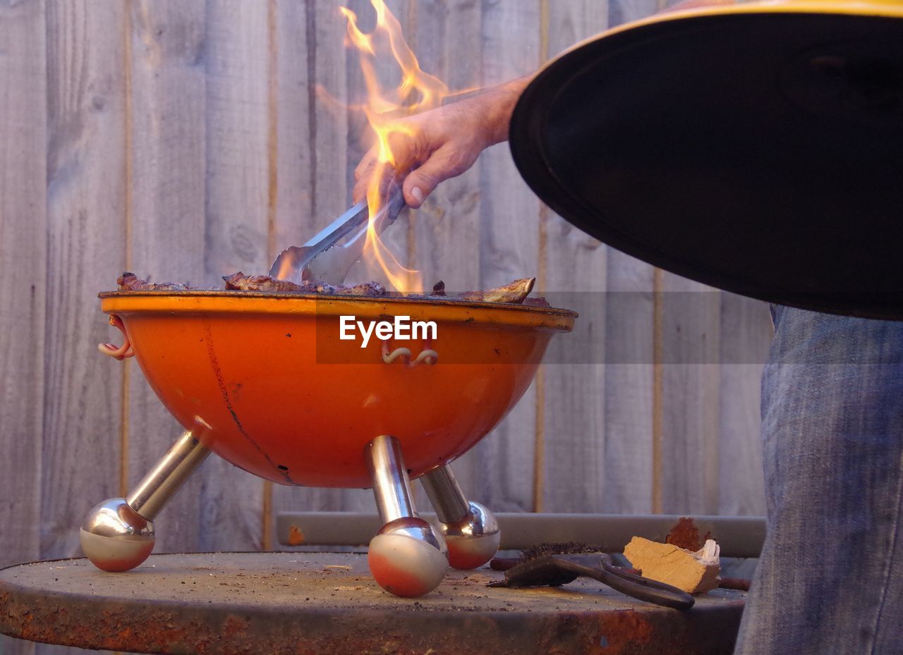 Man cooking meat in flames of barbecue grill